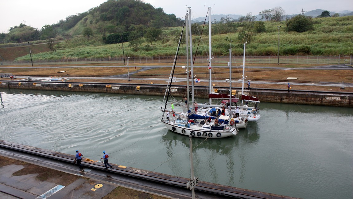 Workers guide the three sailboats